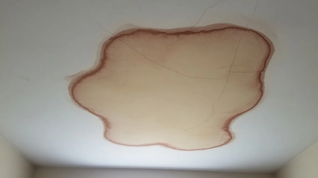 Large brown water stain spreading across the living room ceiling of a Cincinnati home after a leak from above
